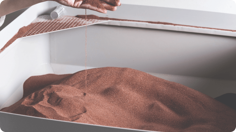 Hand mit durchfließendem Granat über einem Schleifmittelbehälter